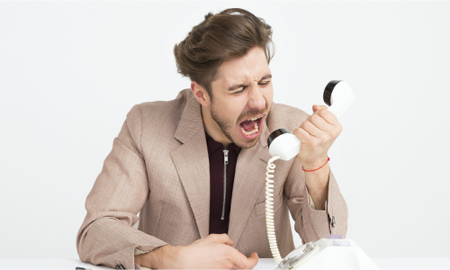 Man yelling angrily into a wired phone