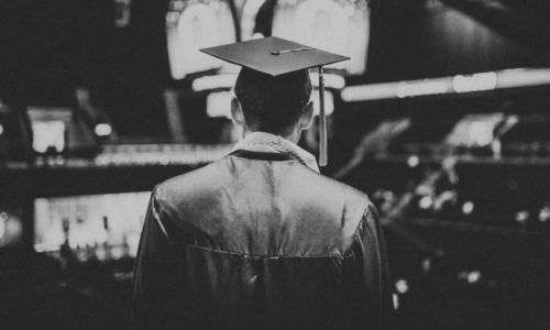 a black and white photo of the back of a graduate wearing a cap and gown