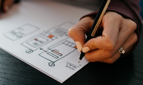A hand working on a UX wireframe
