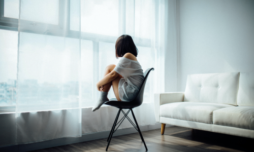 A woman sitting in a chair looking out the window.