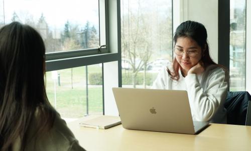 Student sitting at a table working on a laptop