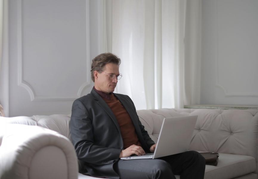 a man wearing a suit is on his laptop in a quiet setting