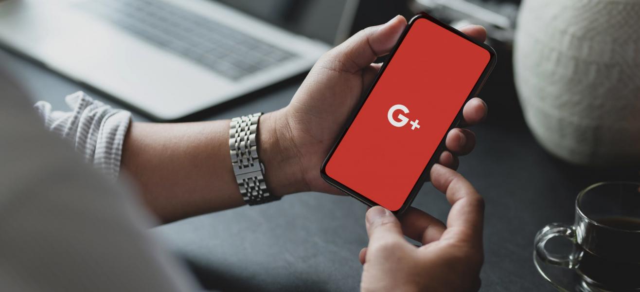 a man holding a phone with Google+ displayed on screen