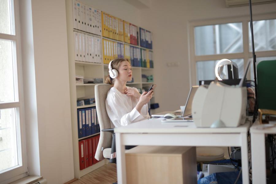 a girl sitting at her desk listening to music and browsing on her phone