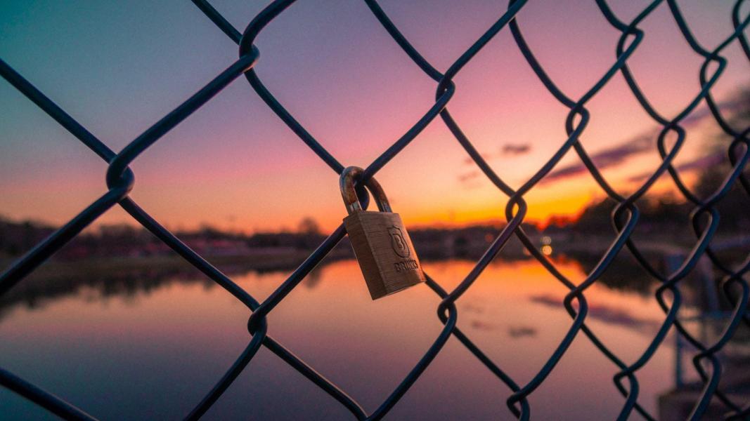 an image of a lock locked on a fence against beautiful sunset