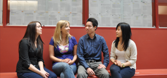 Four students chatting with each other while sitting down.