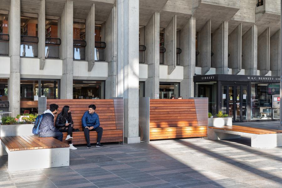 Image of 3 students sitting outside of SFU Burnaby Campus Library