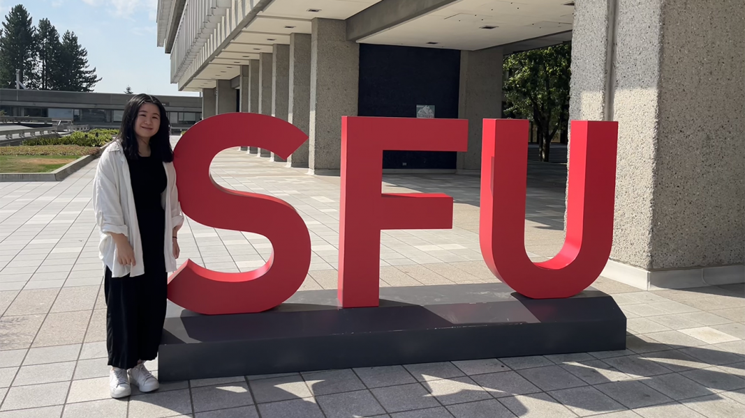 girl standing beside SFU sign