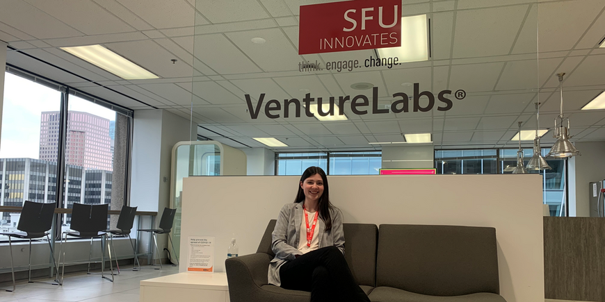 Amy sitting on a sofa, with the SFU VentureLabs logo behind her
