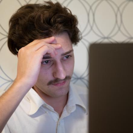 Man looks at laptop disappointedly 
