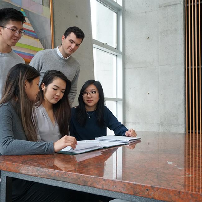 a group of SFU students looking at a notebook