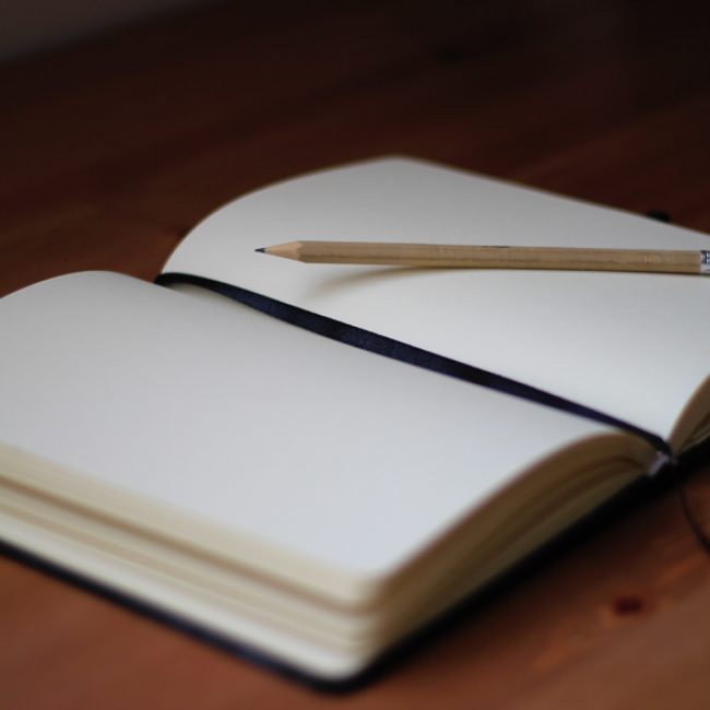 An empty journal laying open with a pencil resting on it. 