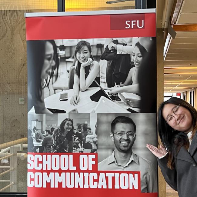 Brianna standing in front of a Communication Banner 