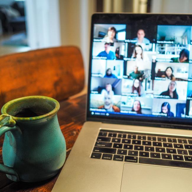 laptop showing online meeting with coffee cup beside