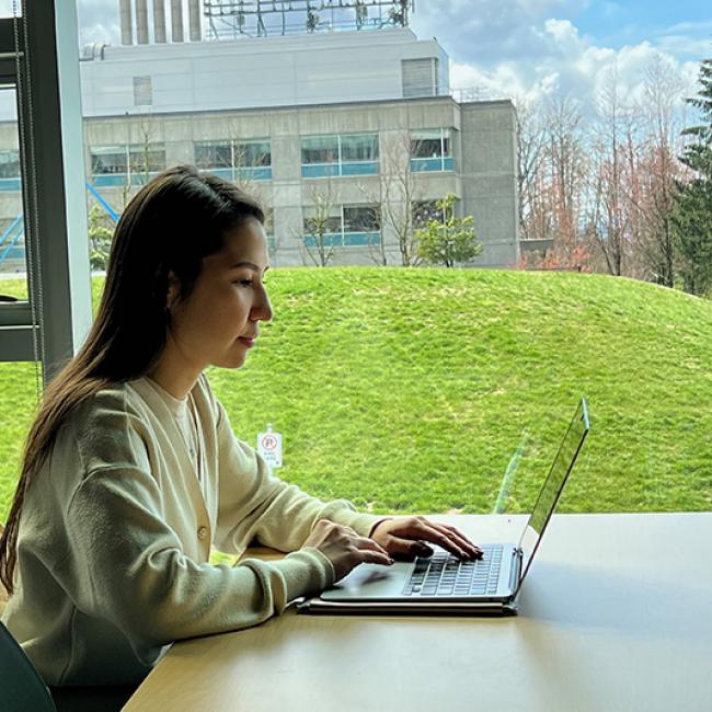 Student on laptop with field and trees in the background