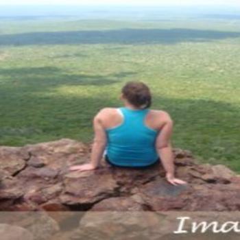 Kaleigh sitting on a cliff staring out to the wilderness