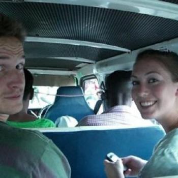 Two people in the bus smiling to the camera