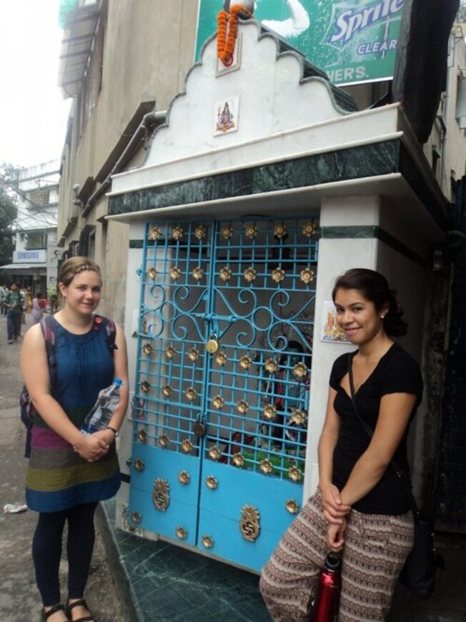 Two of the girls standing in front of a blue gate with gold detailing