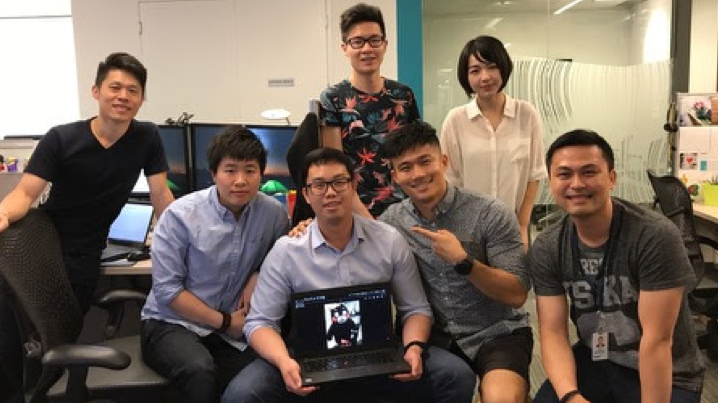 A group of people posing with a laptop showing Business Intelligence tools