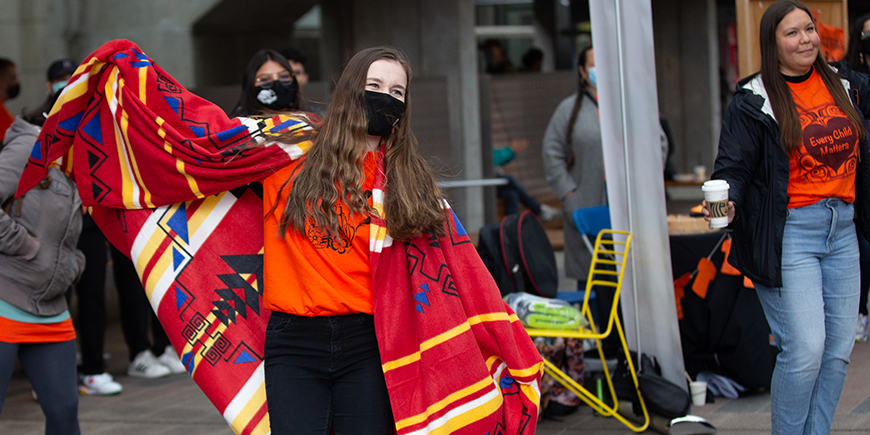 girl with an indigenous blanket doing a dance