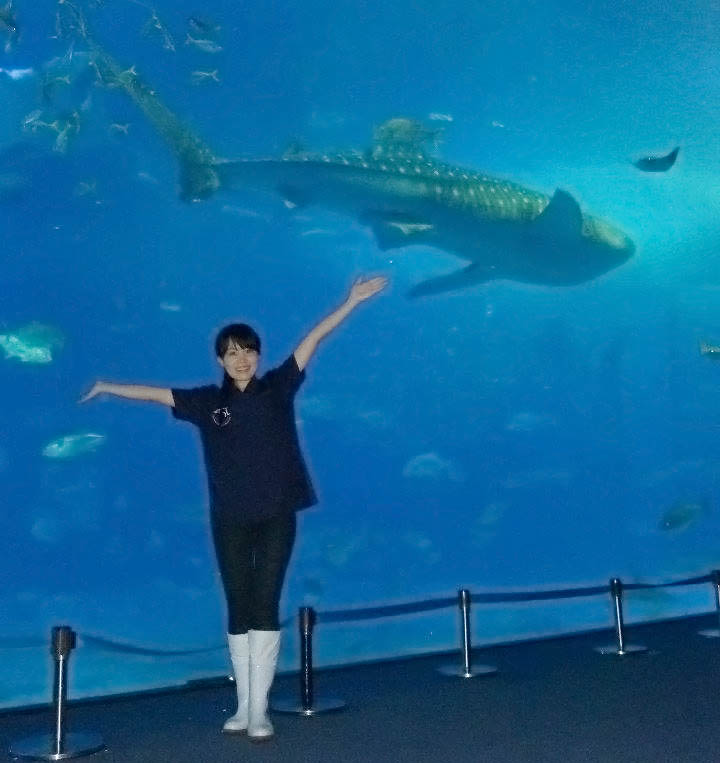 Yuka standing outside a shark tank, smiling with arms in the air