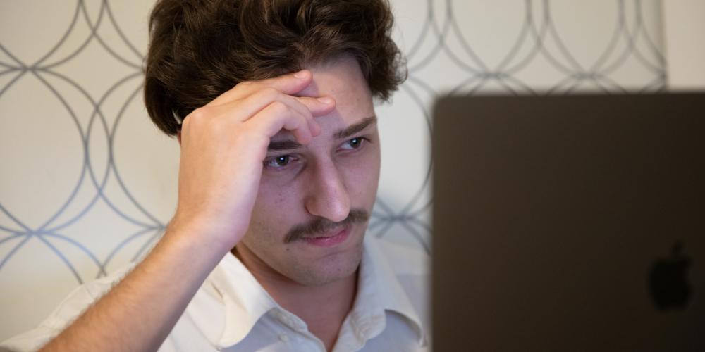 Man looks at laptop disappointedly 