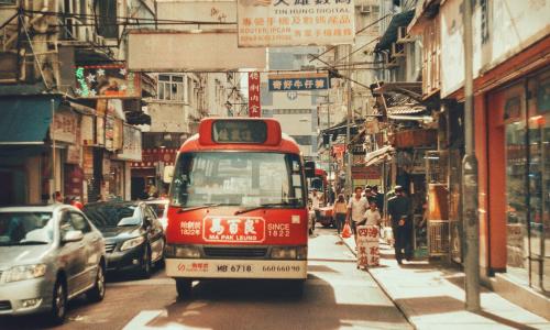 a red bus in the middle of a busy street in Hong Kong