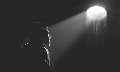 black and white photo of someone looking up to a light source