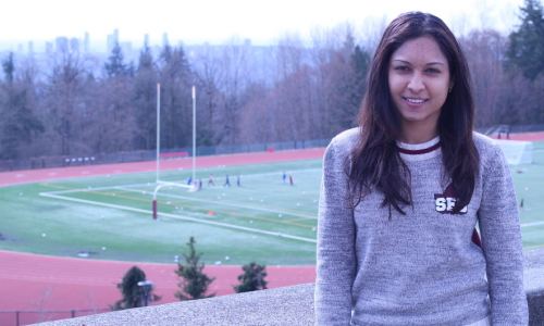 Young woman standing in front of the the SFU track and football field