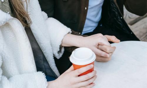 couple holding hands and women holding coffee in other hand 