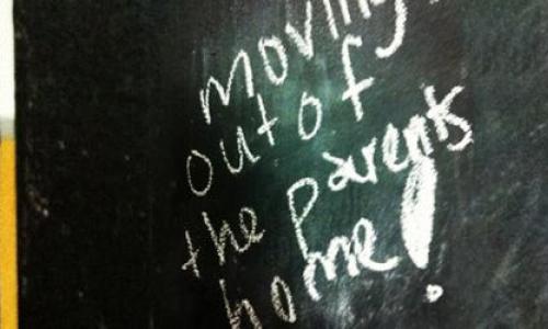 A message on a chalkboard saying "moving out of the parents home!"