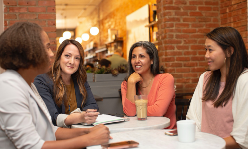 Four people sit around a table in business casual wear.