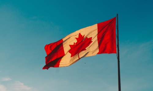 A Canadian flag against the blue sky