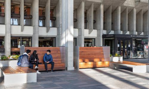 Image of 3 students sitting outside of SFU Burnaby Campus Library