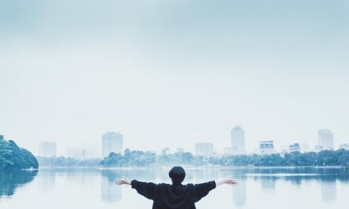 A person with their arms wide open facing the city