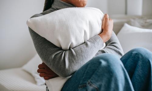A person anxiously hugging a pillow