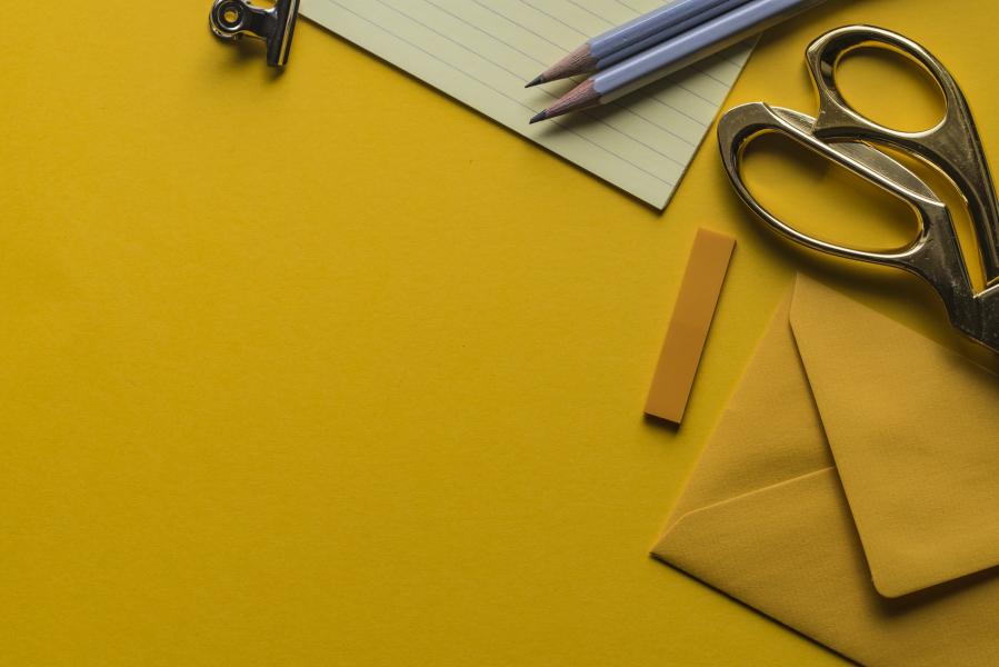 yellow themed flatlay of scissors, papers, and pencils