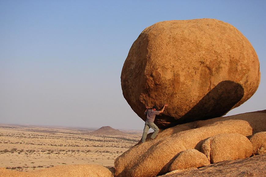 a man pushing a rock uphill