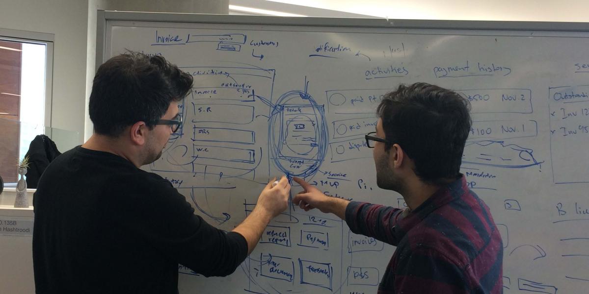 Fahad and his colleague talking about design on a whiteboard