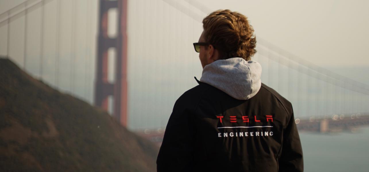 a guy wearing a black Tesla jacket looking at the Golden Gate bridge