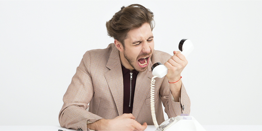 Man yelling angrily into a wired phone