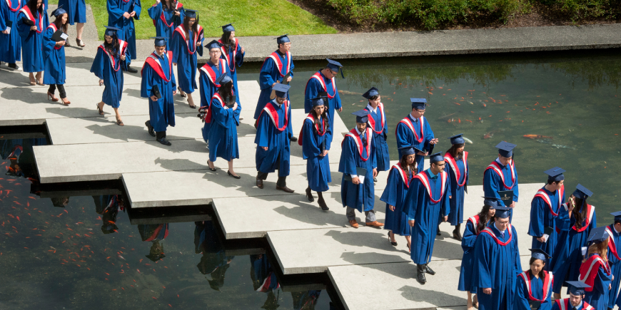 Aerial view of students walking across pond in the Academic Quadrangle during convocation