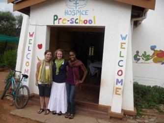 Three women posing in front of a building called 'Hospice Pre-School'