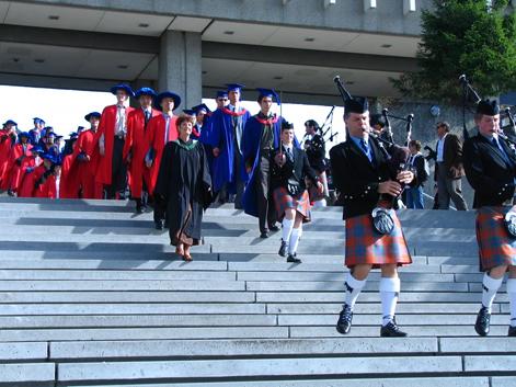 convocation ceremnony; students are walking down the steps of the AQ on SFU Burnaby Campus led by a bagpiper 