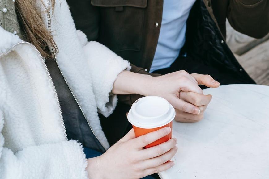 couple holding hands and women holding coffee in other hand 