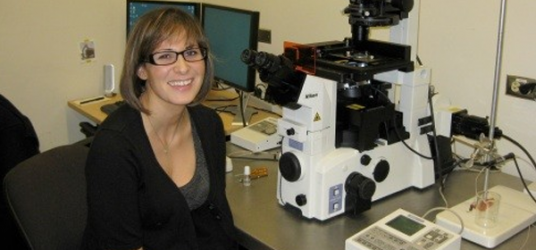 Picture of Jessica beside a microscope