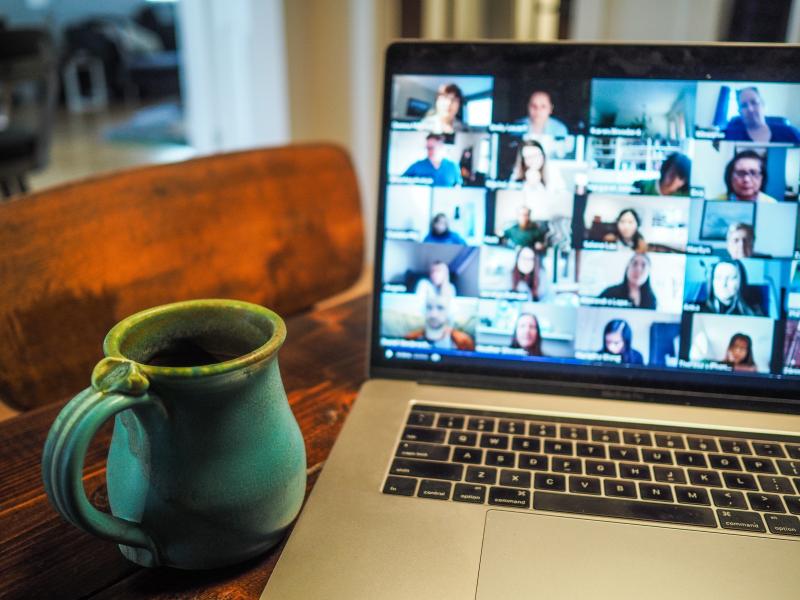 laptop showing online meeting with coffee cup beside