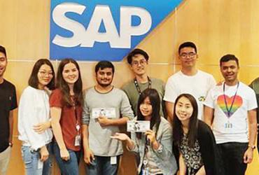 People posing in front of the SAP compant logo 