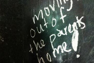 A message on a chalkboard saying "moving out of the parents home!"