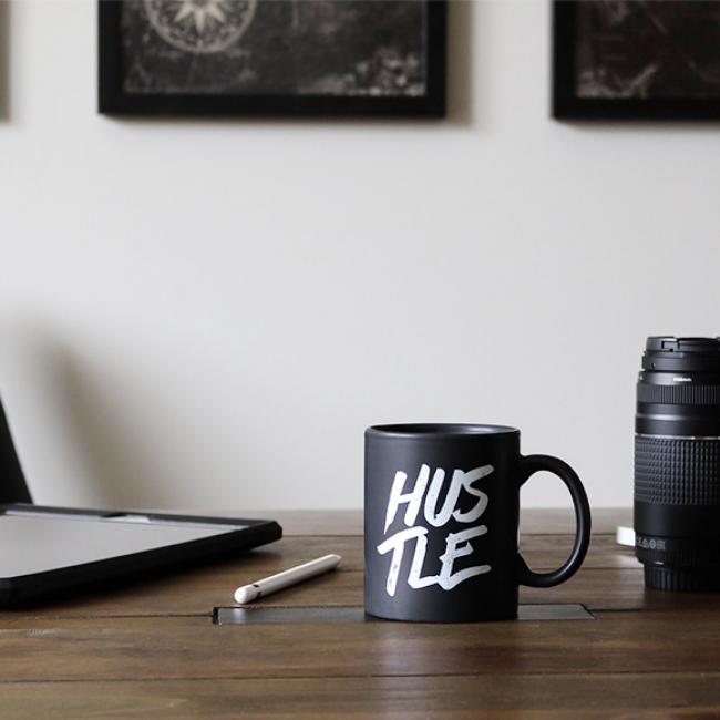 a cup on the desk that says "Hustle"